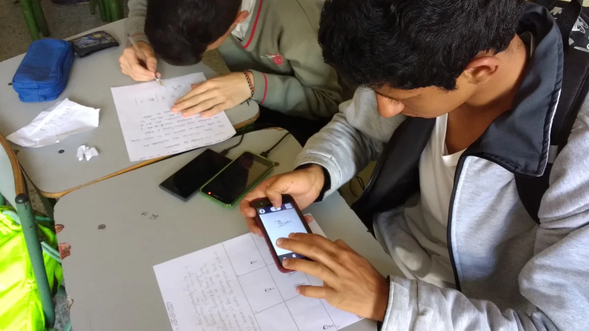 Un élève utilise un téléphone pour préparer une animation image par image sur une table.