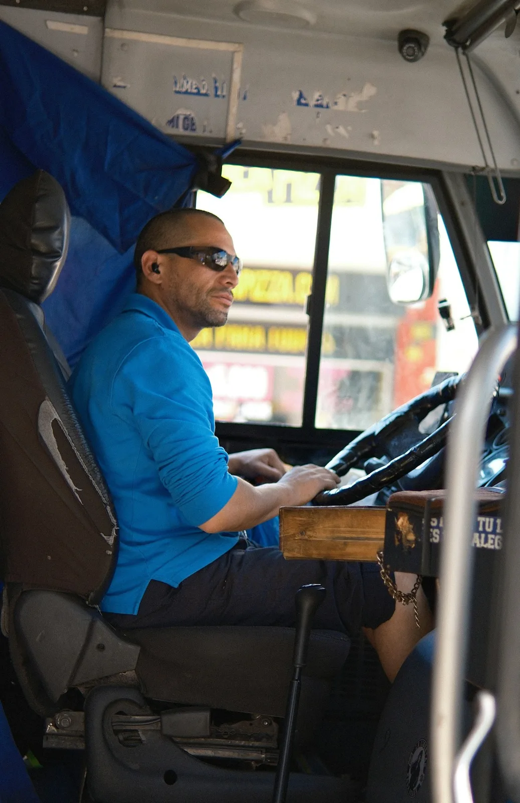 Un conducteur vu de profil au poste de conduite d’un bus.