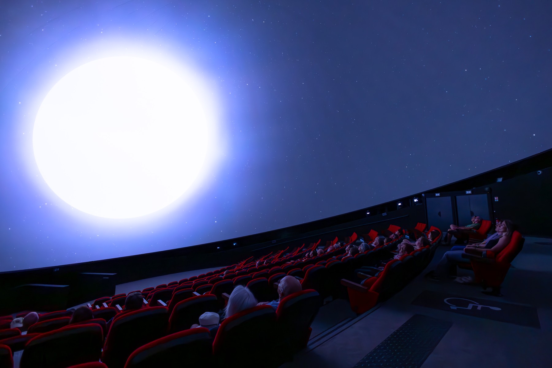 Des spectateurs sous le grand écran en dôme du Planétarium de Vulcania